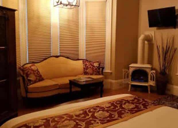 bedroom with sofa and decorated with burgundy accents with fireplace in corner